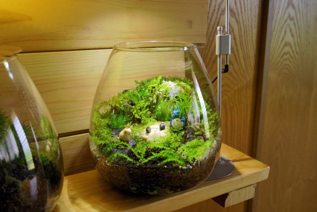 ミニチュアフィギュアを森の景色に配したガラス容器の苔テラリウム作品